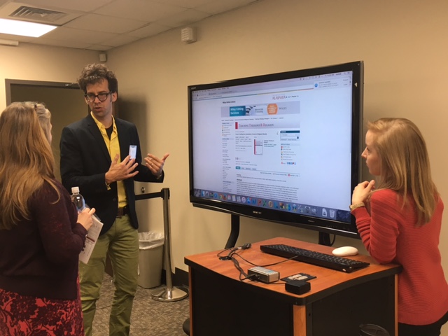 Nathan Lorene talking with students in front of a monitor that displays his research.